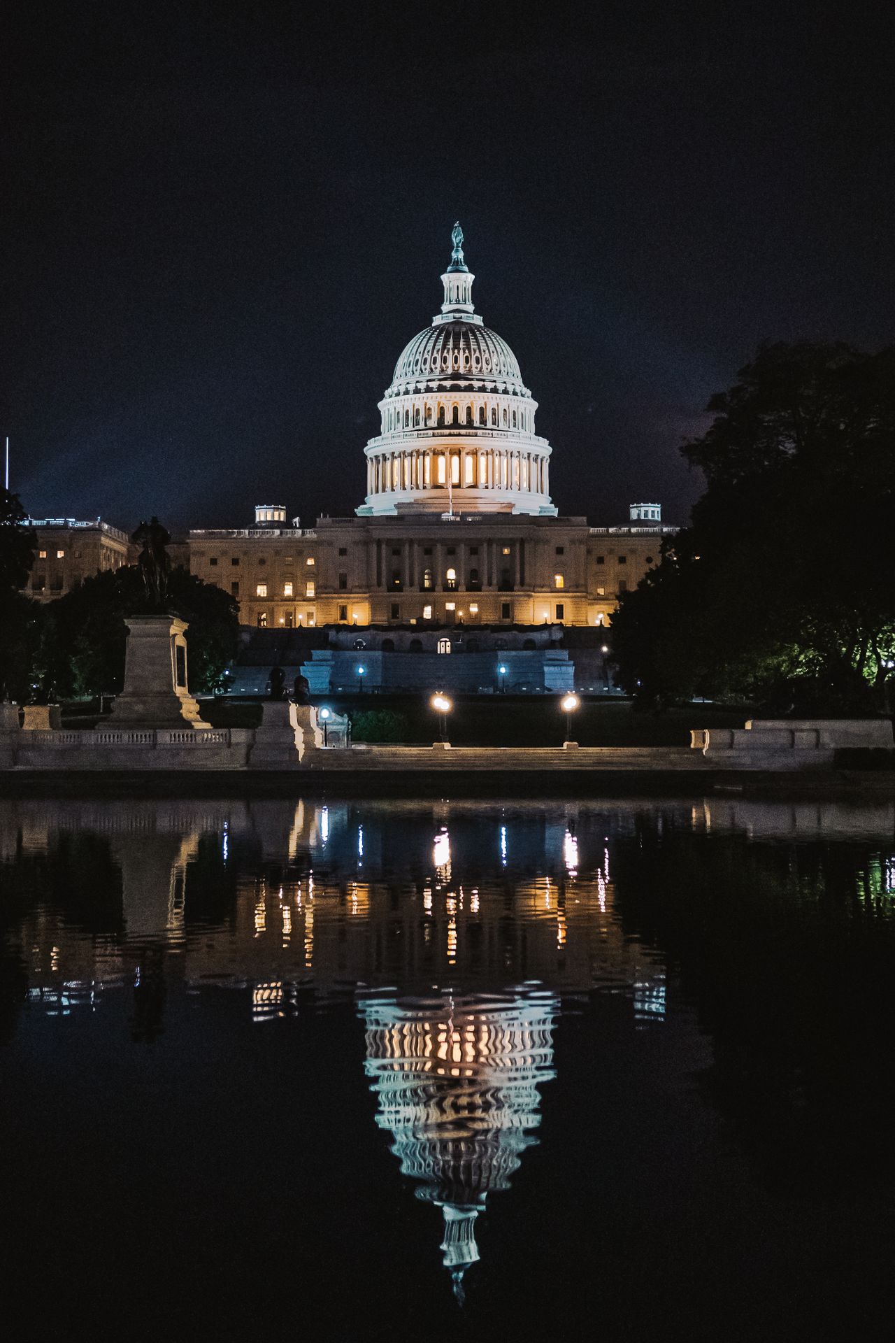 U.S. Capitol building illuminated at night and reflected in the reflecting pool
